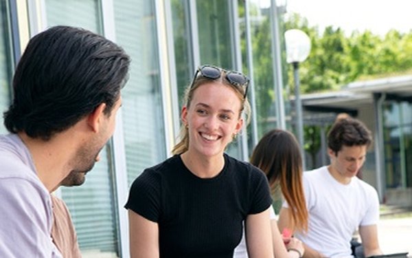 Studierende sitzen auf dem Campus und lernen im Freien, Gruppenarbeit, Studium, Austausch