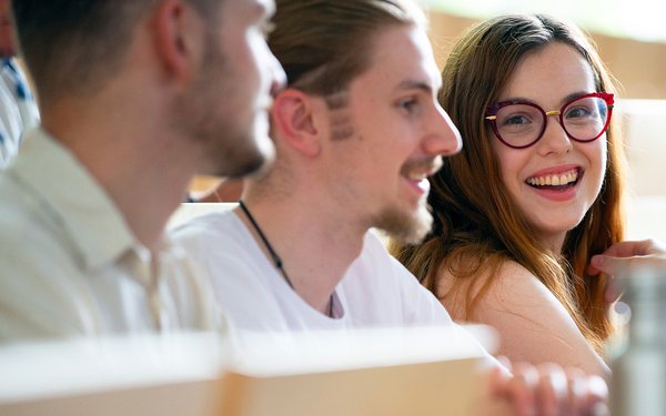 Lächelnde Studentin mit anderen Studierenden im Hörsaal