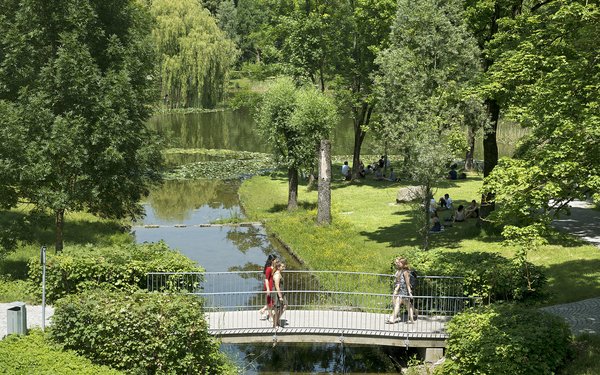 Menschen laufen über Brücke am Campussee