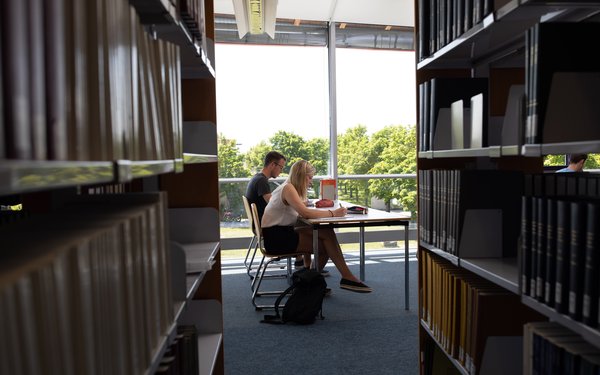 Studenten in der Bibliothek mit Bücherregalen und Ausblick