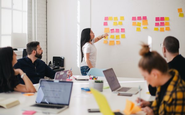 Postits an der Wand, Mitarbeiter am Besprechungstisch