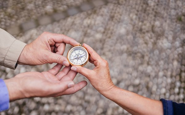 Gemeinsam auf Kurs: Drei Hände halten zusammen einen Kompass