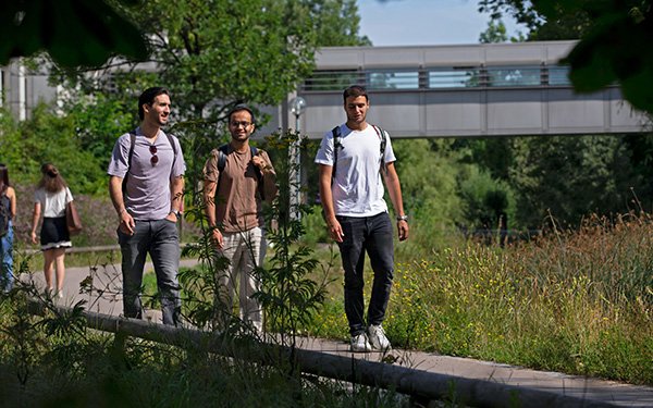 Studierende laufen über den Campus vor der Bibliothek