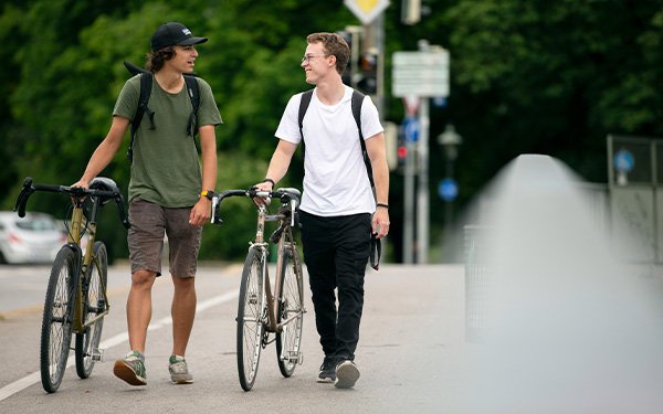 Zwei Studenten schieben ihre Fahrräder in Augsburg