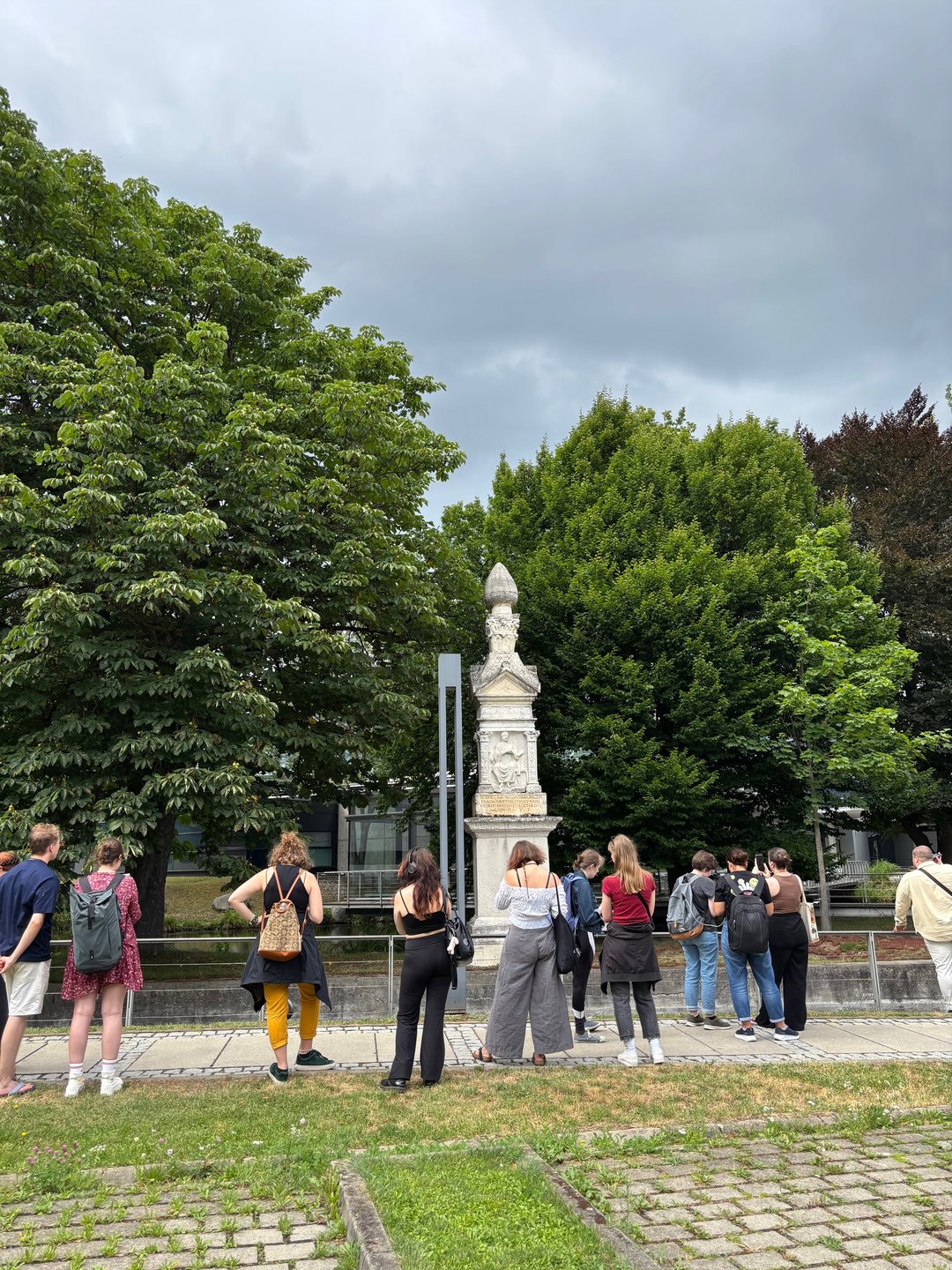 Exkursionsgruppe von Studierenden in Augsburg-Oberhausen vor römischem Grabdenkmal