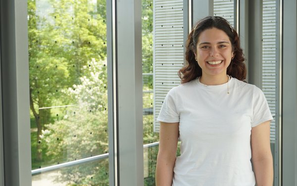 Dr. Beatriz Pérez González steht vor einem Glasfenster und lächelt in die Kamera.