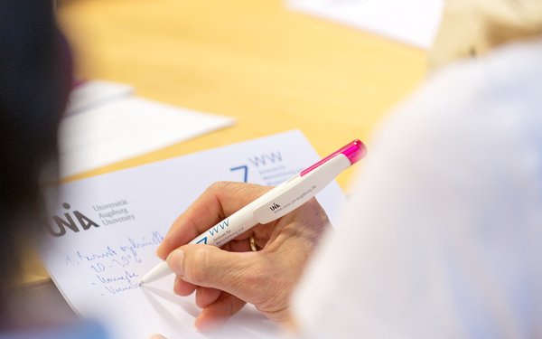 Stift und Block mit ZWW-Logo und Universitätslogo