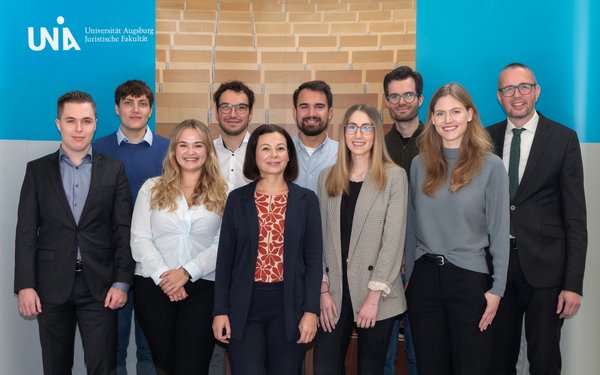 Gruppenbild der Lehrstuhlmitarbeiter von Professor Hellgardt vor einem Banner der Juristischen Fakultät.
