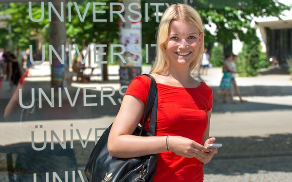 Studentin bei Straßenbahnhaltestelle Universität