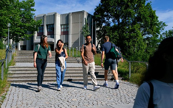 Studierende laufen über den Campus vor der Bibliothek