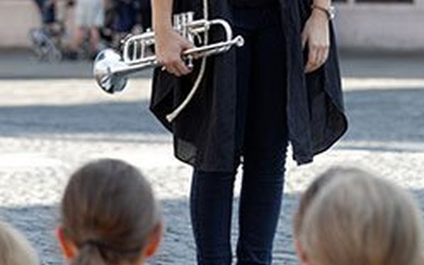 zeigt eine Türmerin auf dem Rathausplatz vor Kindern beim Kinderkonzert im Rahmen des Augsburger Friedensfestes