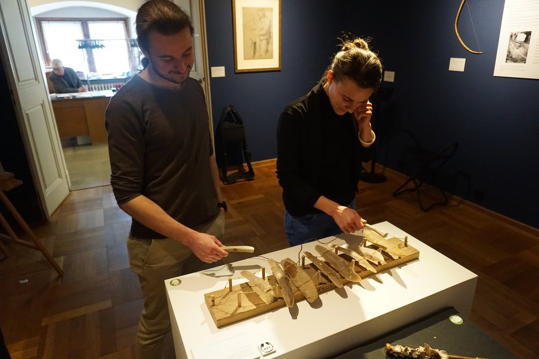 Exkursionsteilnehmer beim Ausprobieren eines rekonstruierten antiken Musikinstruments im Martin von Wagner Museum in Würzburg.