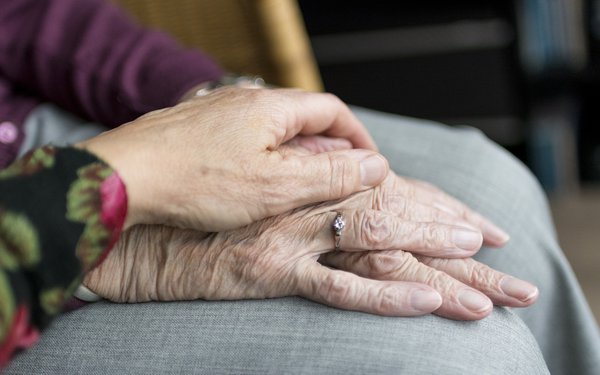 Eine junge Hand liegt auf zwei alten Händen
