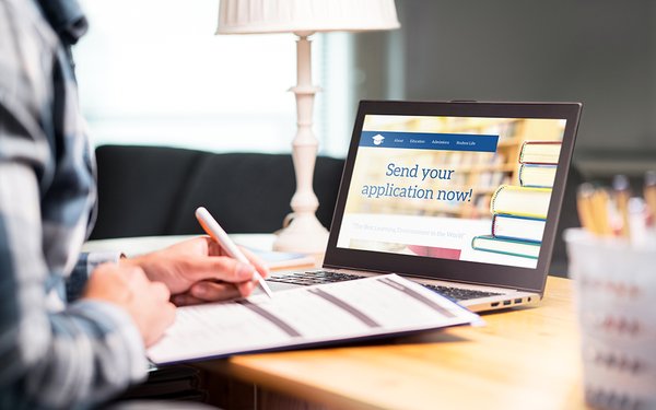 Eine Frau sitzt am Laptop, auf dem "Send your application now" zu lesen ist