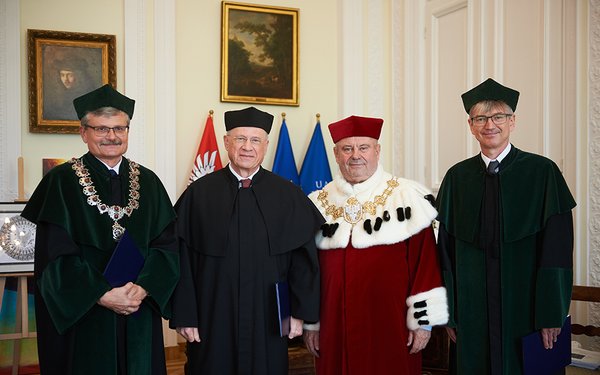 Four men in traditional academic clothing, three of which are wearing black gowns and one, second from right, wearing a red gown (Rector).