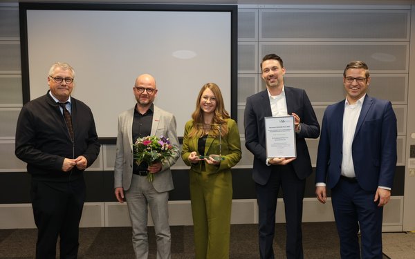 Die fünf Personen stehen nebeneinander und lächeln in die Kamera.