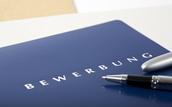 Blaue Bewerbungsmappe mit Aufdruck "Bewerbung" und Stift