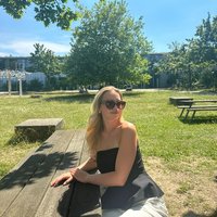 Linda, 2. Semester, sitzt auf einer Bank im Grünen vor der juristischen Fakultät
