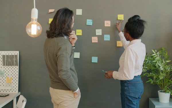 Zwei Leute brainstormen mit Haftnotizen an der Wand