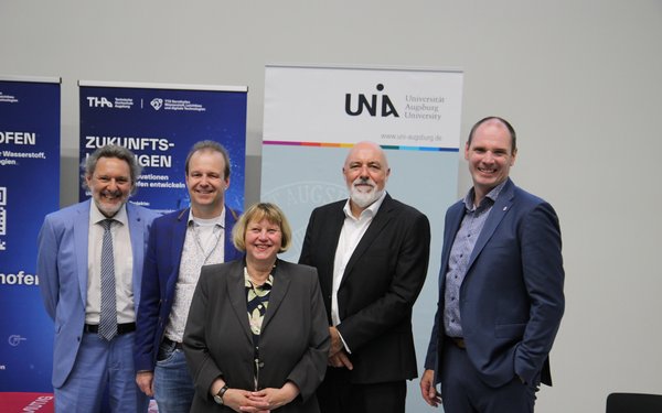 The five people smile into the camera.
