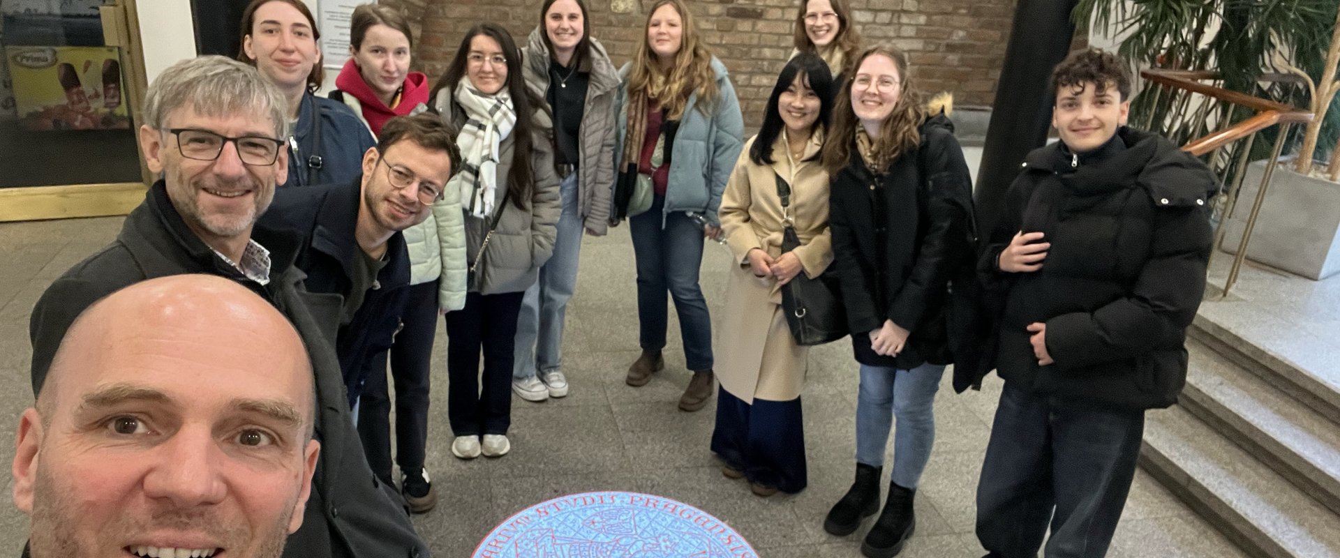 Es ist ein Gruppenbild mit dem Logo der Karls-Universität zu sehen.