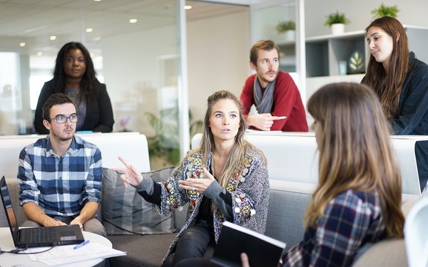 Team aus sechs Menschen diskutiert am Arbeitsplatz