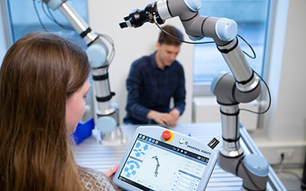 Robotergestützte Produktion: Zwei Studierende arbeiten mit einem Roboterarm