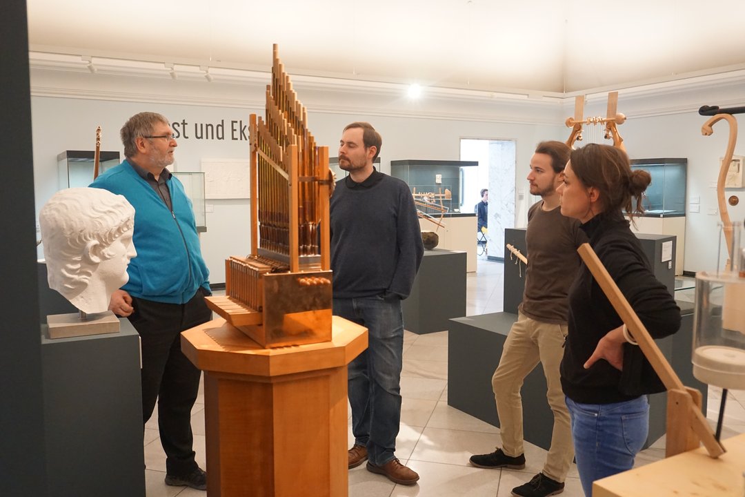ExkursionsteilnehmerInnen an einer Rekonstruktion einer antiken Wasserorgel im Martin von Wagner Museum in Würzburg.