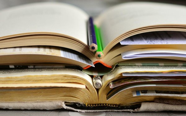 Aufgeschlagenes Buch mit Stiften und Zetteln