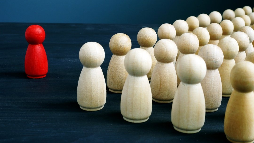 Eine rote Spielfigur steht mehrern weißen Spielfiguren gegenüber.