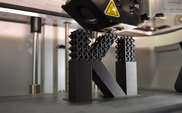 Ein 3D Drucker erstellt eine Skulptur des Begriffs KI