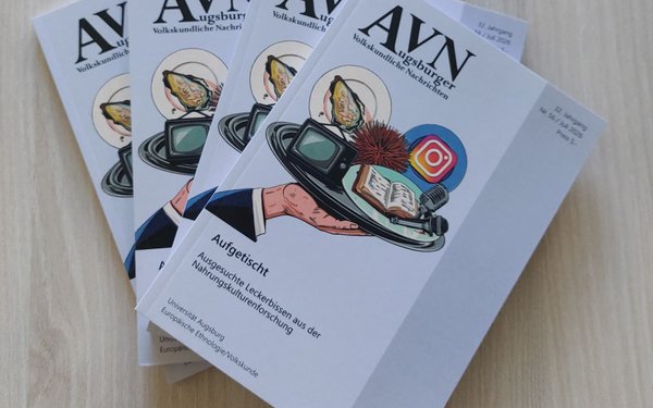 Vier Ausgaben der AVN Ausgabe 56 liegen aufgefächert auf einem Holztisch
